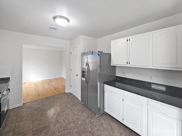 kitchen featuring stainless steel fridge, dark countertops, white cabinets, and baseboards
