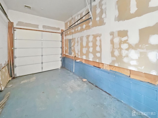 garage featuring concrete block wall and electric panel