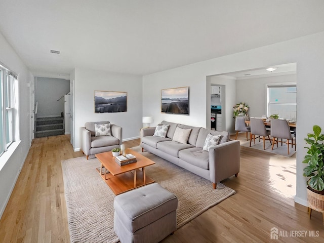 living room featuring stairs, light wood-style floors, and baseboards