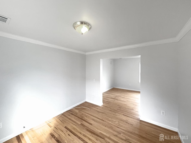spare room with ornamental molding, baseboards, and wood finished floors