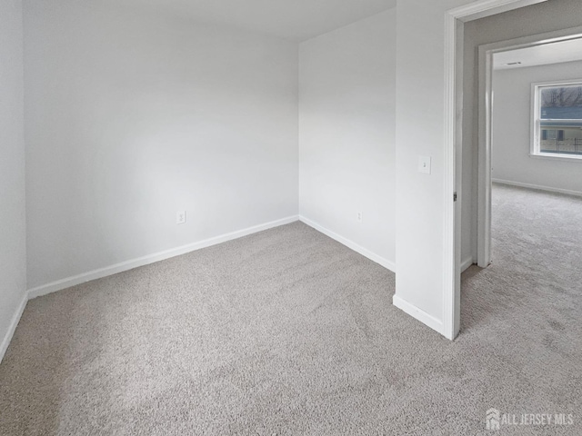 carpeted empty room featuring baseboards