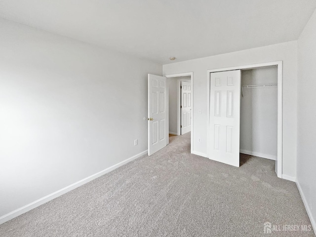 unfurnished bedroom with carpet flooring, baseboards, and a closet