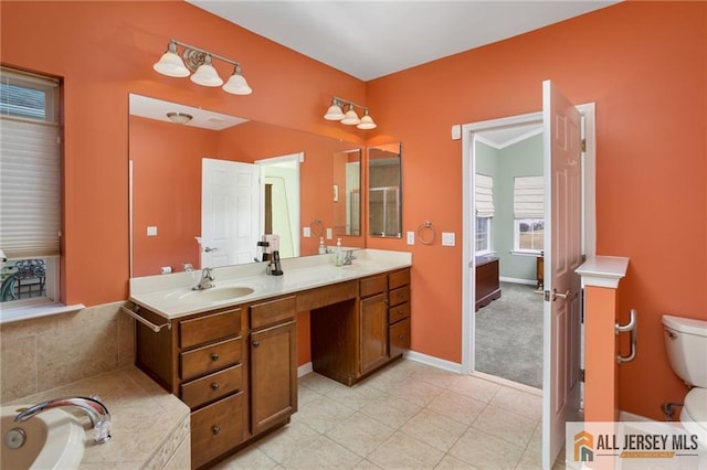 bathroom featuring a garden tub, toilet, a sink, tile patterned floors, and double vanity