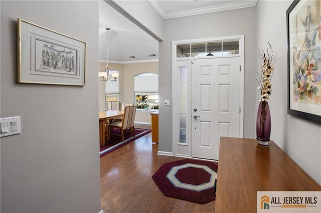 entryway featuring dark wood-style floors, baseboards, crown molding, and an inviting chandelier