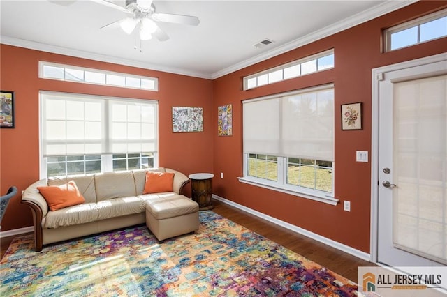 living room with plenty of natural light, visible vents, wood finished floors, and ornamental molding