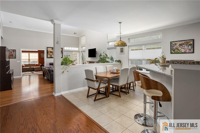 dining area featuring light wood-type flooring, decorative columns, baseboards, and crown molding