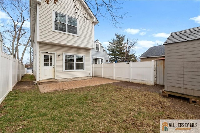 rear view of house with a patio, a shed, a yard, a fenced backyard, and an outdoor structure