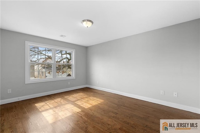 unfurnished room with visible vents, baseboards, and wood finished floors