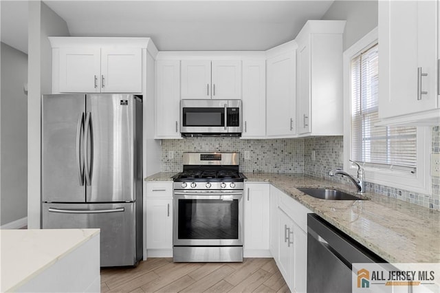 kitchen with a sink, decorative backsplash, appliances with stainless steel finishes, and white cabinets