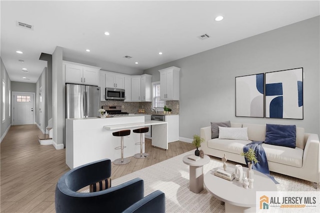 living area featuring recessed lighting, visible vents, and light wood finished floors