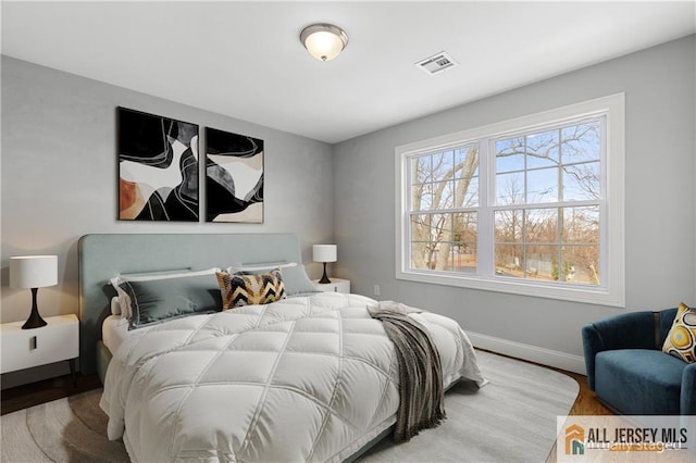 bedroom featuring visible vents, baseboards, and wood finished floors