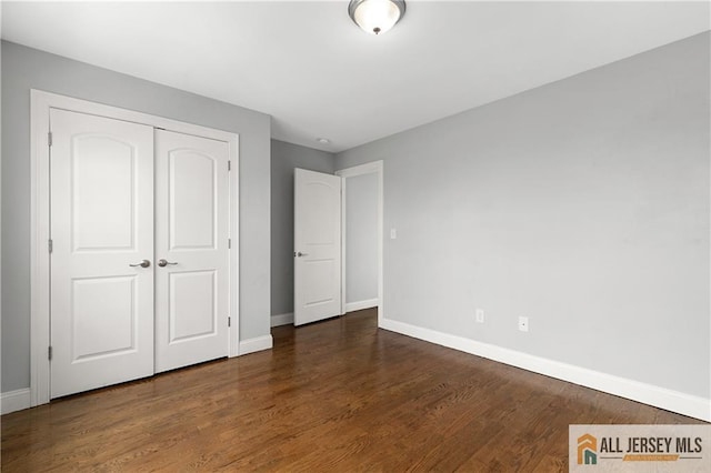 unfurnished bedroom with a closet, baseboards, and wood finished floors