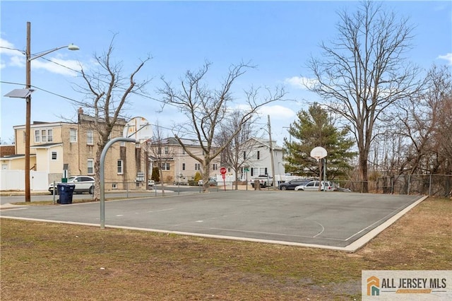 view of basketball court featuring a residential view, community basketball court, a lawn, and fence