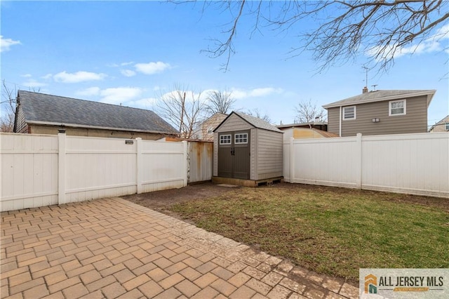 view of yard with a storage unit, a fenced backyard, an outdoor structure, and a patio area