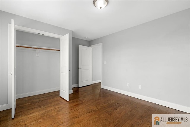 unfurnished bedroom with wood finished floors, a closet, and baseboards