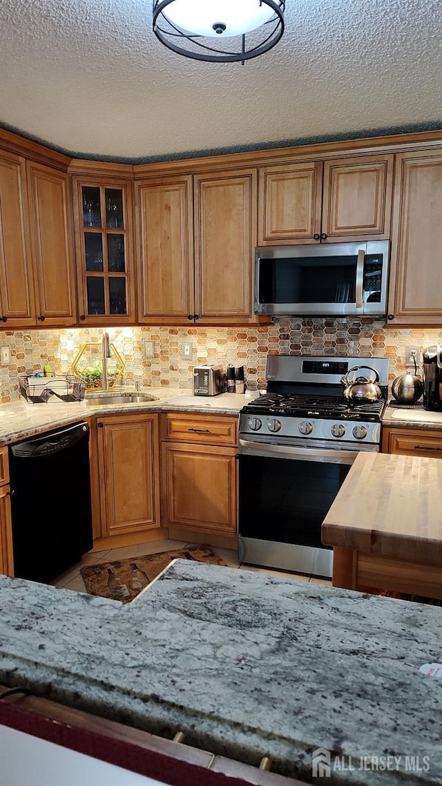 90 Clay St, North Brunswick, NJ 08902 - kitchen featuring stainless steel appliances, a sink, backsplash, light stone countertops, and a textured ceiling