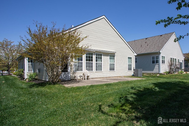 rear view of house featuring central air condition unit, a lawn, and a patio area
