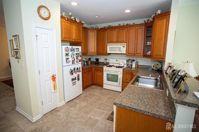 kitchen featuring brown cabinetry, a sink, and white appliances