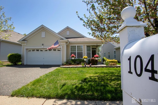 ranch-style home featuring an attached garage, a front lawn, and aphalt driveway
