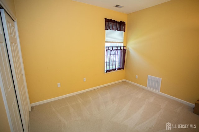 empty room with visible vents, baseboards, and light colored carpet