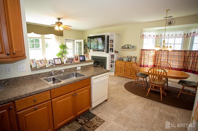 kitchen with ceiling fan, white dishwasher, dark countertops, a fireplace, and a sink