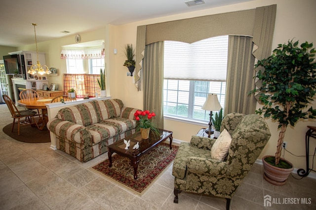 tiled living area with an inviting chandelier and visible vents