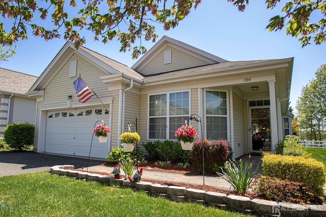 single story home with a shingled roof, an attached garage, and aphalt driveway
