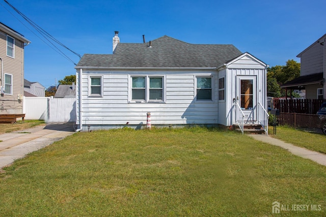 bungalow with roof with shingles, a chimney, board and batten siding, a front yard, and fence