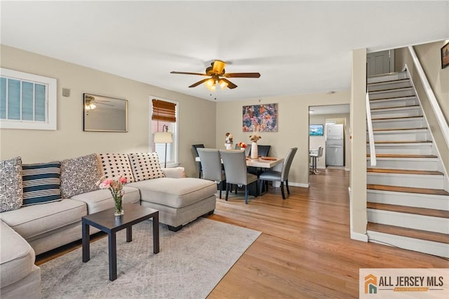 living room featuring stairway, a ceiling fan, light wood-style flooring, and baseboards