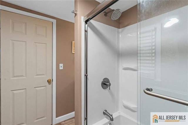 full bath featuring tub / shower combination and baseboards