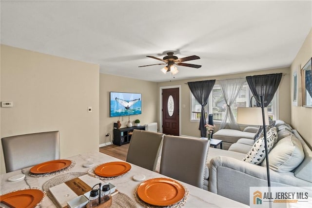 dining room with radiator heating unit, ceiling fan, wood finished floors, and baseboards