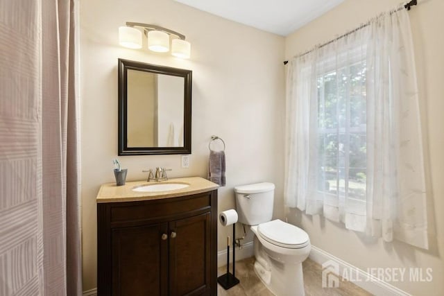 bathroom with baseboards, toilet, and vanity