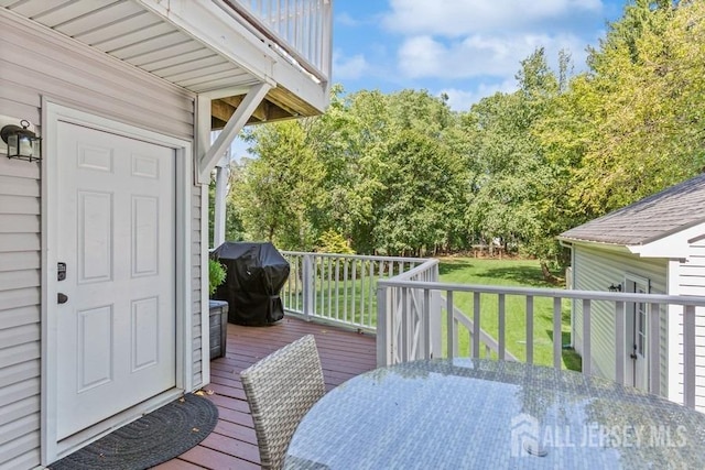 wooden terrace featuring area for grilling, outdoor dining area, and a yard