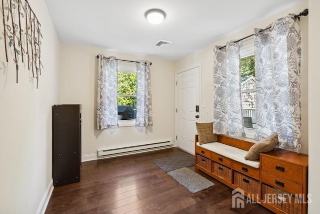 interior space featuring dark wood finished floors, visible vents, a baseboard heating unit, and baseboards