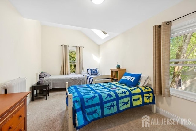 bedroom with multiple windows, vaulted ceiling with skylight, radiator, and carpet flooring