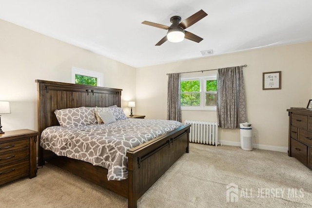 bedroom with visible vents, light carpet, radiator heating unit, baseboards, and ceiling fan