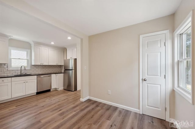 763 Prospect Ave, Old Bridge, NJ 08879 - kitchen featuring appliances with stainless steel finishes, dark countertops, decorative backsplash, light wood-style floors, and white cabinets