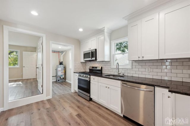 763 Prospect Ave, Old Bridge, NJ 08879 - kitchen featuring appliances with stainless steel finishes, light wood finished floors, gas water heater, tasteful backsplash, and white cabinetry