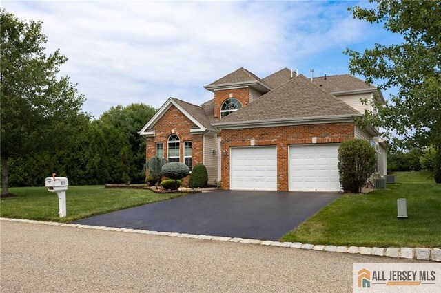 front of property featuring central AC unit, a garage, and a front lawn