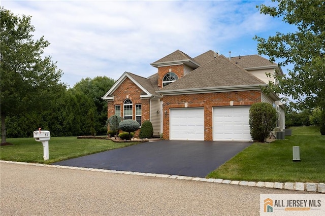 view of front of property with roof with shingles, a front lawn, aphalt driveway, and brick siding