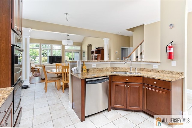 kitchen with light tile patterned floors, light stone counters, a peninsula, a sink, and appliances with stainless steel finishes