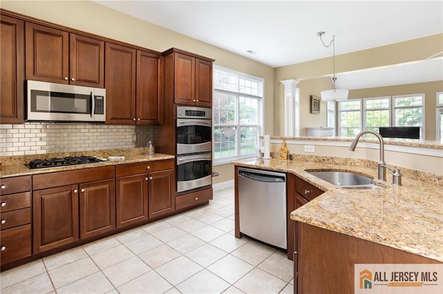 kitchen featuring light tile patterned floors, stainless steel appliances, a sink, light stone countertops, and tasteful backsplash