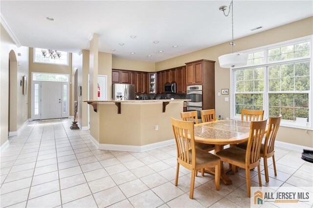 dining space with arched walkways, light tile patterned floors, recessed lighting, visible vents, and baseboards