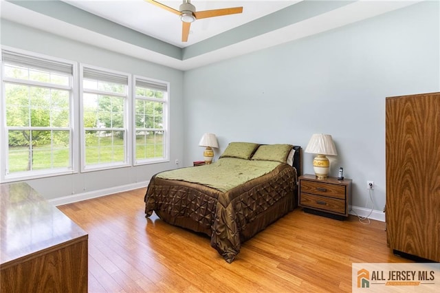 bedroom featuring a ceiling fan, light wood-style flooring, and baseboards