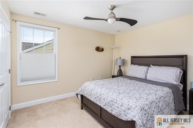 bedroom with light colored carpet, ceiling fan, visible vents, and baseboards