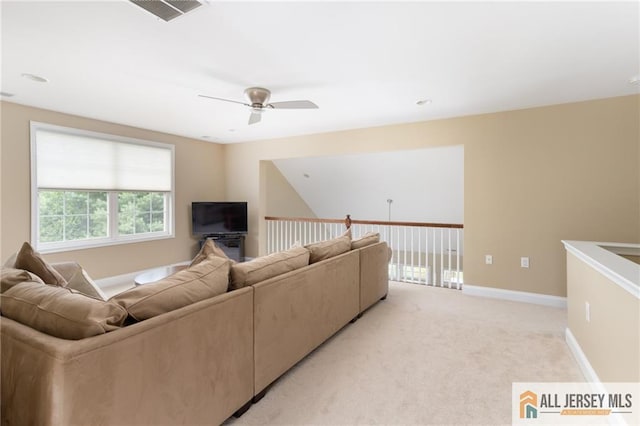 living area with baseboards, visible vents, a ceiling fan, and light colored carpet