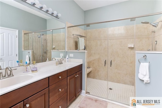 full bath with double vanity, a shower stall, a sink, and tile patterned floors