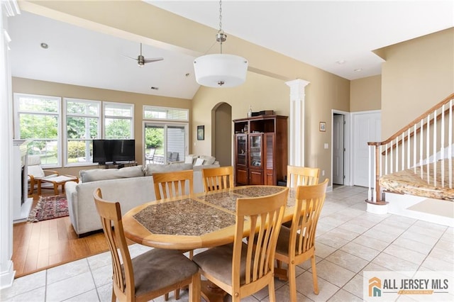 dining room with decorative columns, light tile patterned floors, ceiling fan, high vaulted ceiling, and stairs