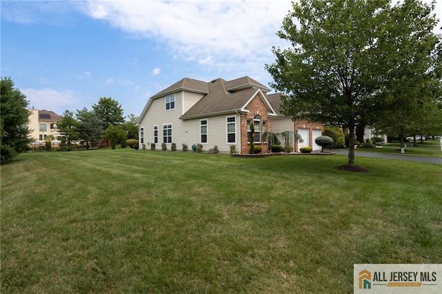 view of front facade with a front yard, brick siding, driveway, and an attached garage