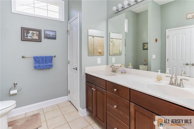 bathroom with toilet, tile patterned flooring, double vanity, and a sink